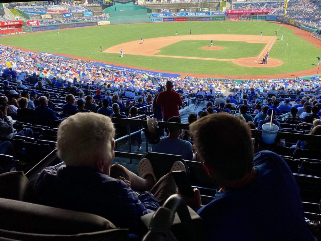 Closeup of two people watching a Royals baseball game from the stands.