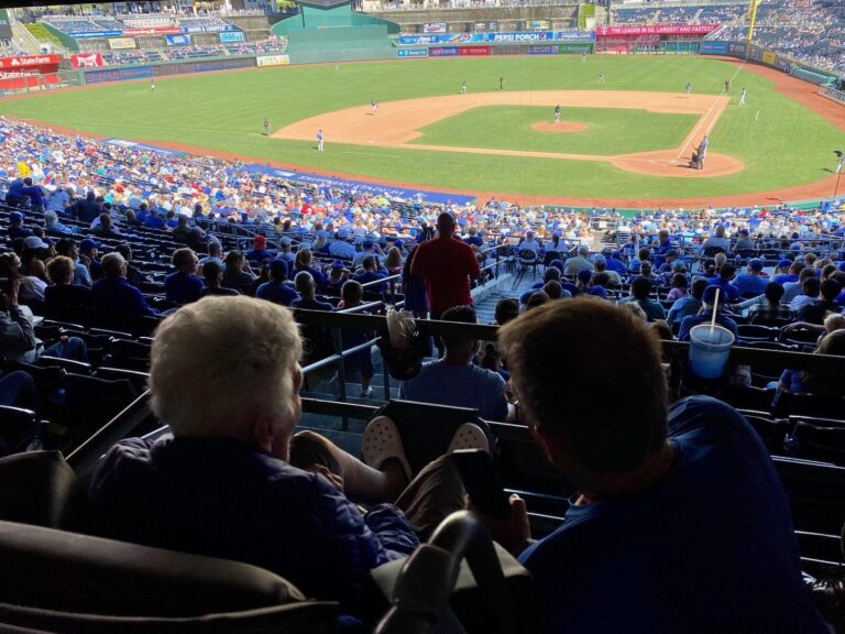 Closeup of two people watching a Royals baseball game from the stands.