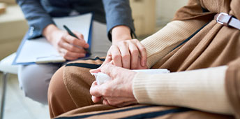 Female Psychologist Holding Hand Of Senior Woman During Therapy Session