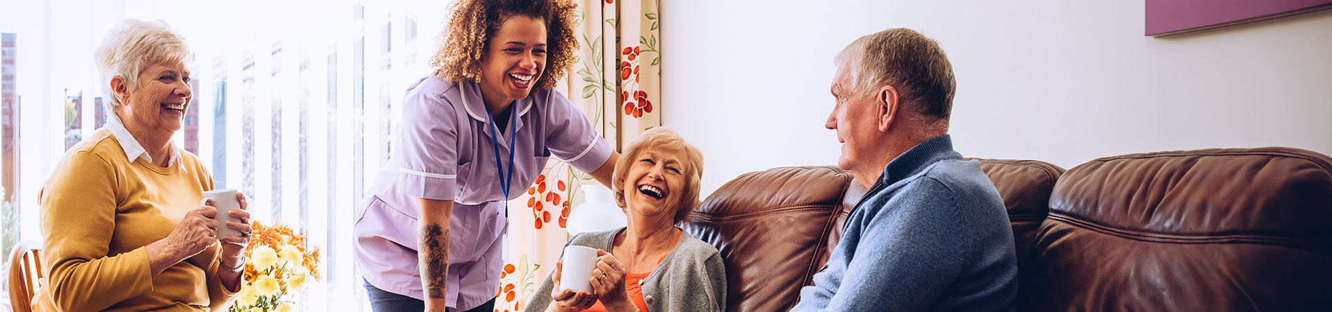 Group Of Senior People Smiling And Chatting With Caregiver
